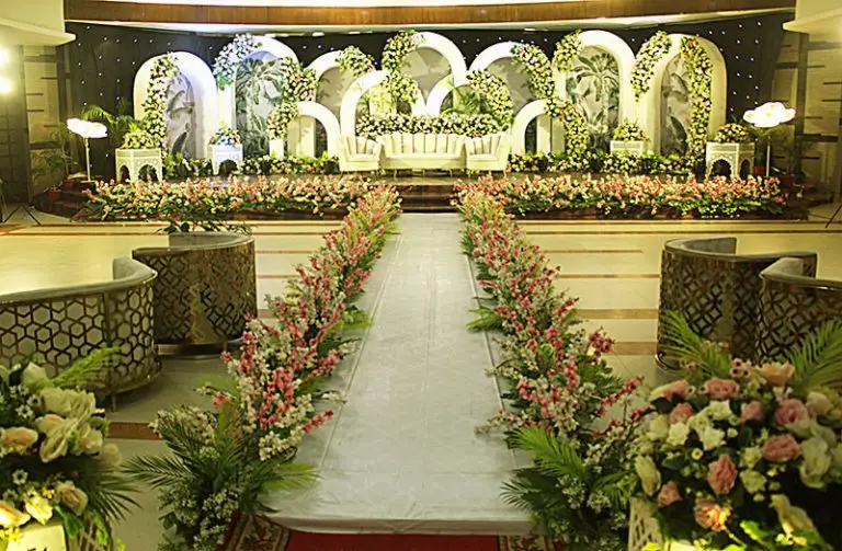 Elegant wedding reception stage decoration with floral backdrop and lighting setup