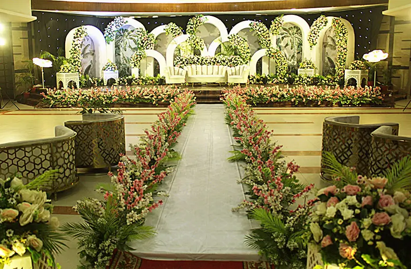 Elegant wedding reception stage decoration with floral backdrop and lighting setup